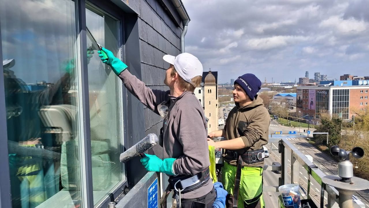 To vinduespudsere fra Cosmus Polering arbejder på en facade i højden